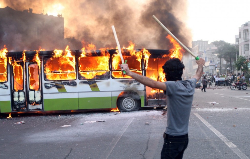 An Iranian protester stands next to a burning bus during clashes with Iranian police at a demonstration in Tehran on June 20, 2009. Thousands of Iranians clashed with police as they defied an ultimatum from supreme leader Ayatollah Ali Khamenei for an end to protests over last week's disputed presidential election. AFP PHOTO/ALI SAFARI