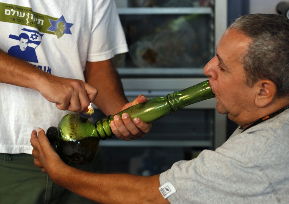 A man sits on a wheelchair as he is helped to smoke cannabis in Tel Aviv